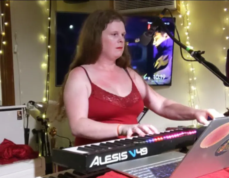 Azalea Jane playing an Alesis keyboard under string lights.