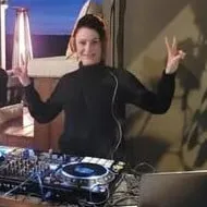 Michelle Badion behind a DJ setup at dusk, throwing peace signs.