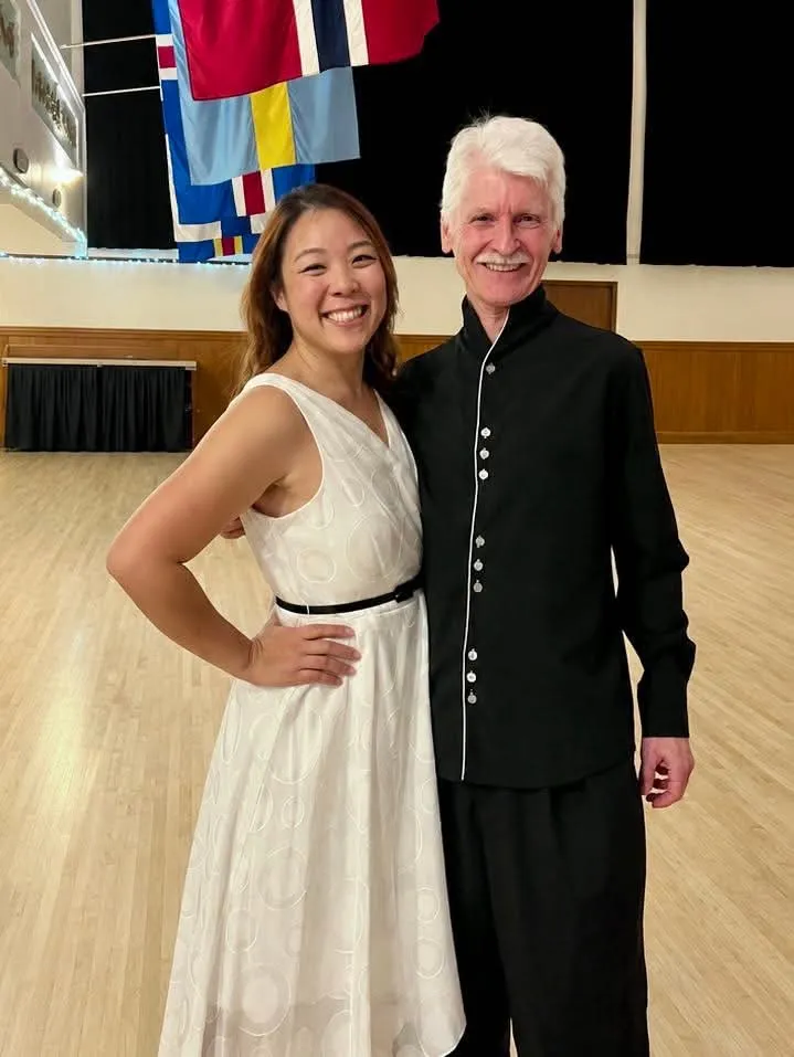 Sandy Ninh and Steve Carruthers standing together in a dance hall.